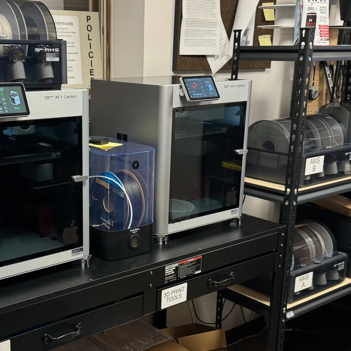 Bambu Lab X1 Carbon 3D printers with AMS material systems and filament racks at Shibui Tech in Bloomington, Indiana