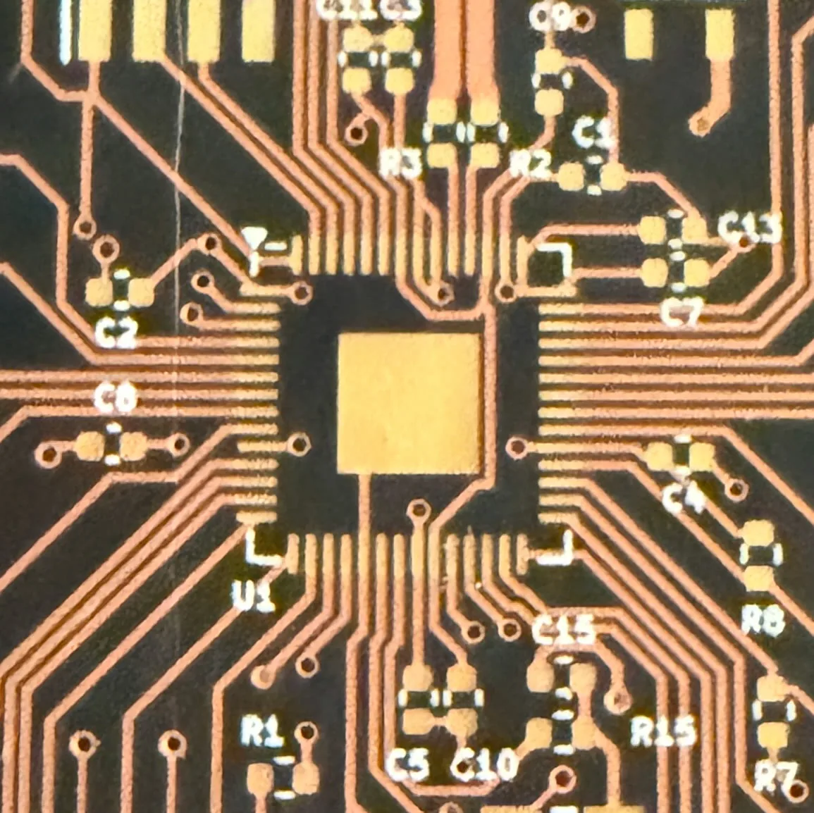 Close-up of a custom printed circuit board layout with QFN footprint and routed traces designed at Shibui Tech